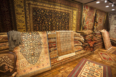 Carpet store with stacks of woven silk and Persian rugs